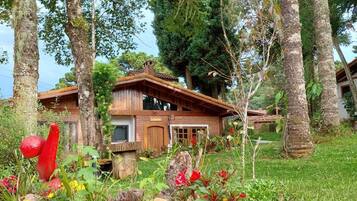 Uma casa de madeira rústica cercada por vegetação exuberante e árvores.