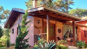 A two-story building with a covered patio area, a brick facade, and a garden with various plants and flowers. - Pousada Anecuém (Camanducaia)