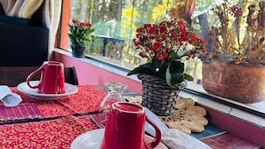 A table with red cups and saucers, a small potted plant, and a wicker basket on a window sill. - Pousada Anecuém (Camanducaia)