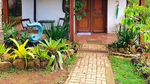 A small, rustic building with a tiled roof, a wooden door, and a sign reading "4 Jacarandá". - Pousada Anecuém (Camanducaia)