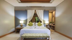 Een slaapkamer met een groot bed, twee nachtkastjes, een bankje en een spiegel.