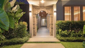 A pathway leading to a building with an ornate entrance, surrounded by well-maintained greenery.