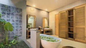 A modern bathroom with a freestanding bathtub, wooden cabinets, and a decorative wall panel.