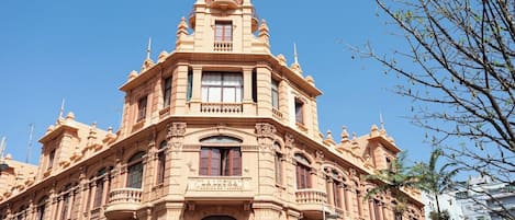Un edificio histórico con arquitectura ornamentada, varios balcones y ventanas amplias.