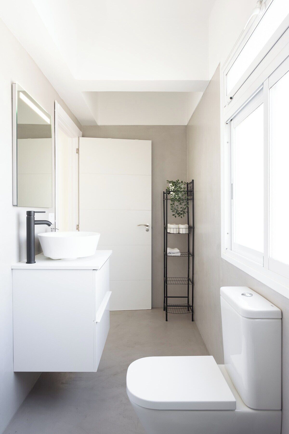 A modern bathroom with a white sink, mirror, and toilet.