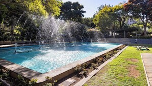 A rectangular swimming pool with multiple water jets, surrounded by a grassy area and trees. - Home2Book Stylish & Bright Apt, Santa Cruz Center (Santa Cruz de Tenerife)