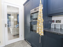 Una cocina moderna con armarios oscuros, horno integrado y microondas. Hay recipientes etiquetados para café y té en la encimera.