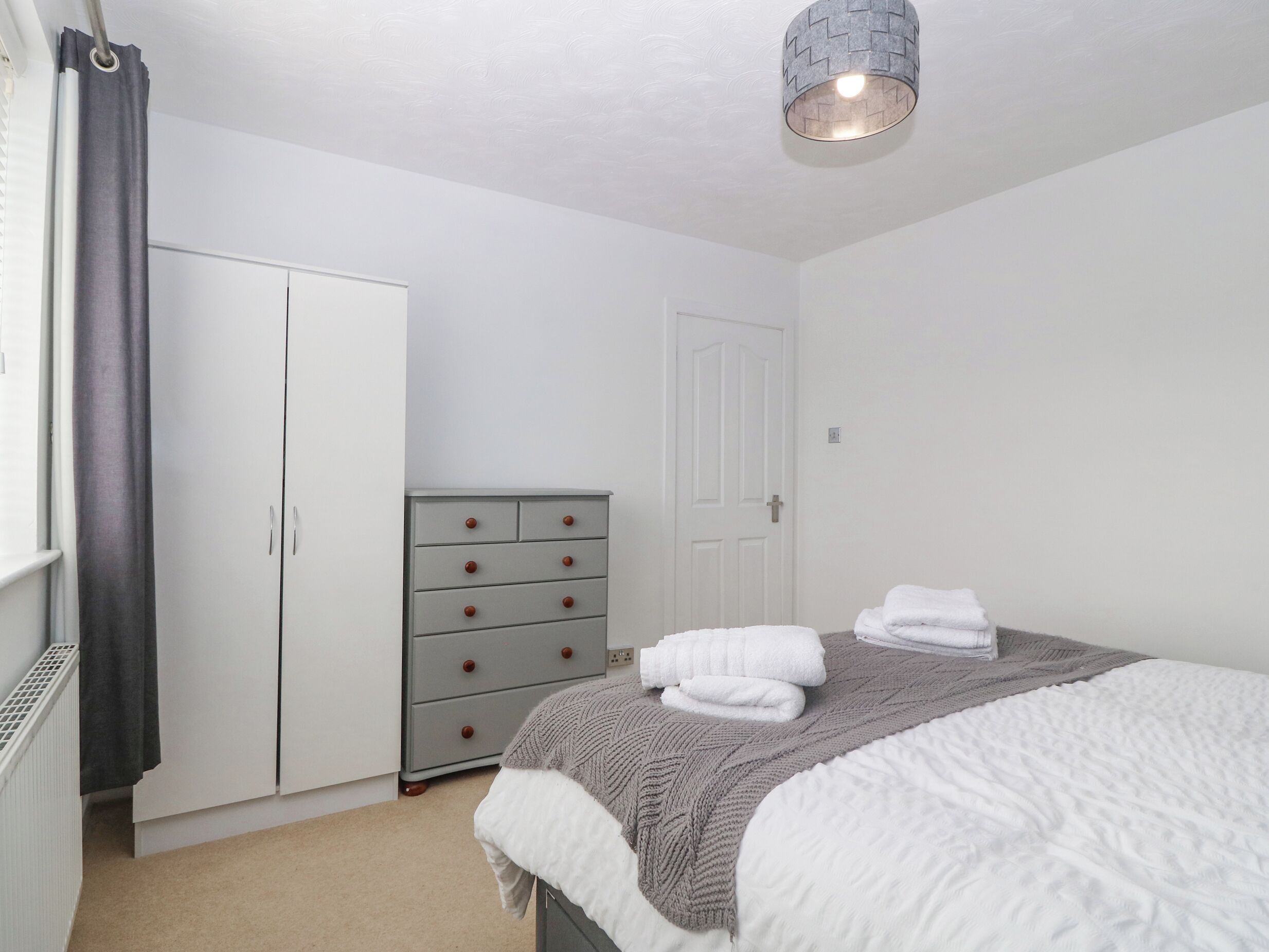 Un dormitorio con cama, cómoda, armario y lámpara de techo.