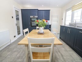 Una cocina moderna con armarios azul oscuro, una mesa de comedor de madera y sillas blancas.