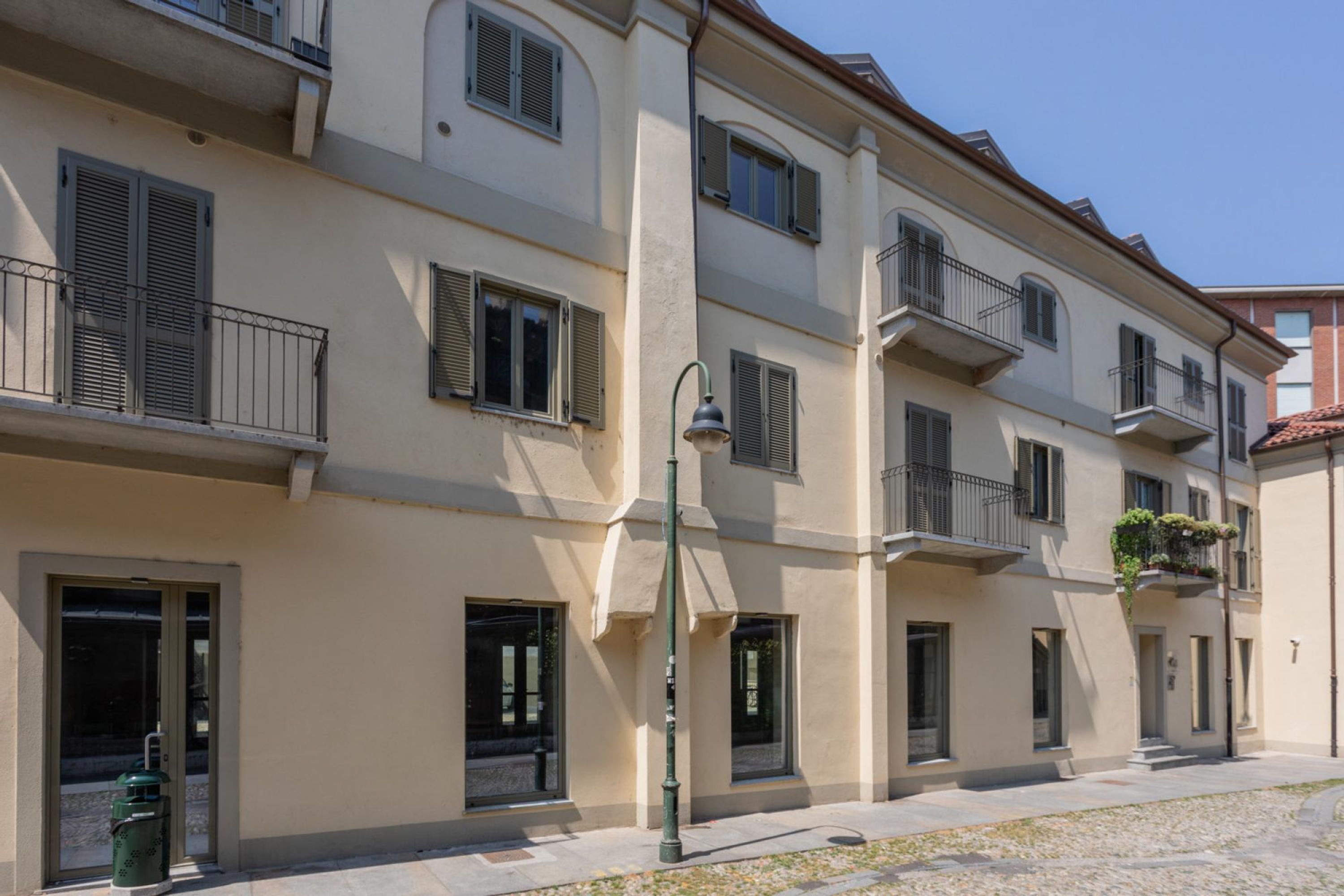 A multi-story residential building with balconies, a street lamp, and a trash bin.