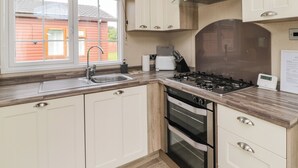 Une cuisine moderne avec des armoires blanches, un évier en acier inoxydable, une cuisinière à gaz et un four encastré.