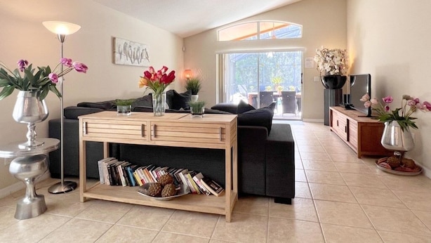 A modern living room with a sofa, coffee table, and decorative plants. - Spacious Family Pool Home With Game Room-588ocb 4 Bedroom Home by RedAwning (Davenport)
