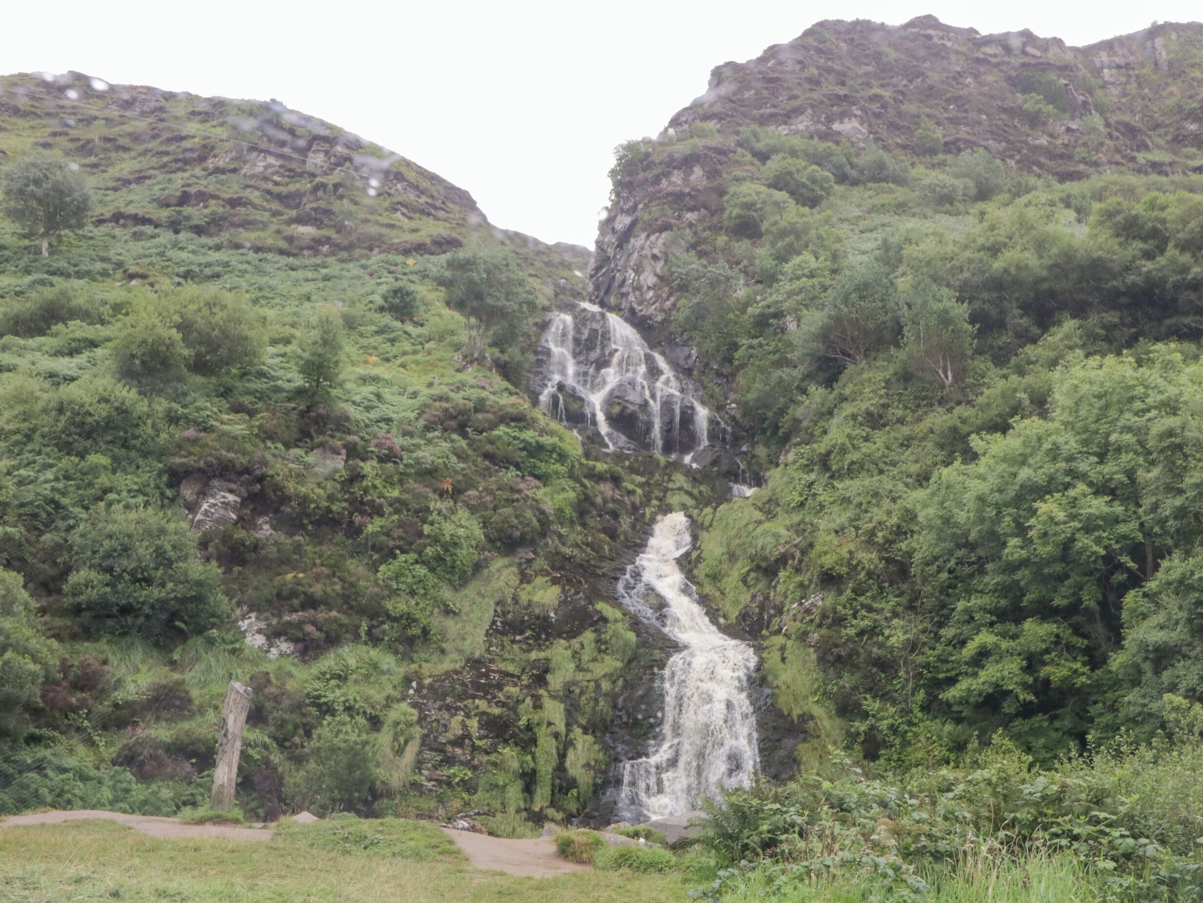 Une cascade se déversant le long d’une falaise rocheuse, entourée d’une végétation luxuriante.