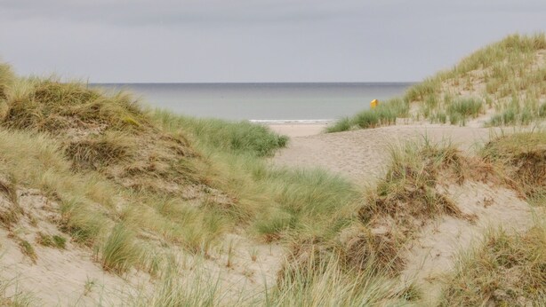 A beach with sand dunes and a yellow lifeguard chair. - Maghera Caves Cottage (Ardara)
