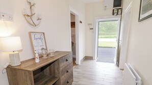 A hallway with a wooden console table, a wall-mounted light, and a sign that reads "Best days." - Maghera Caves Cottage (Ardara)