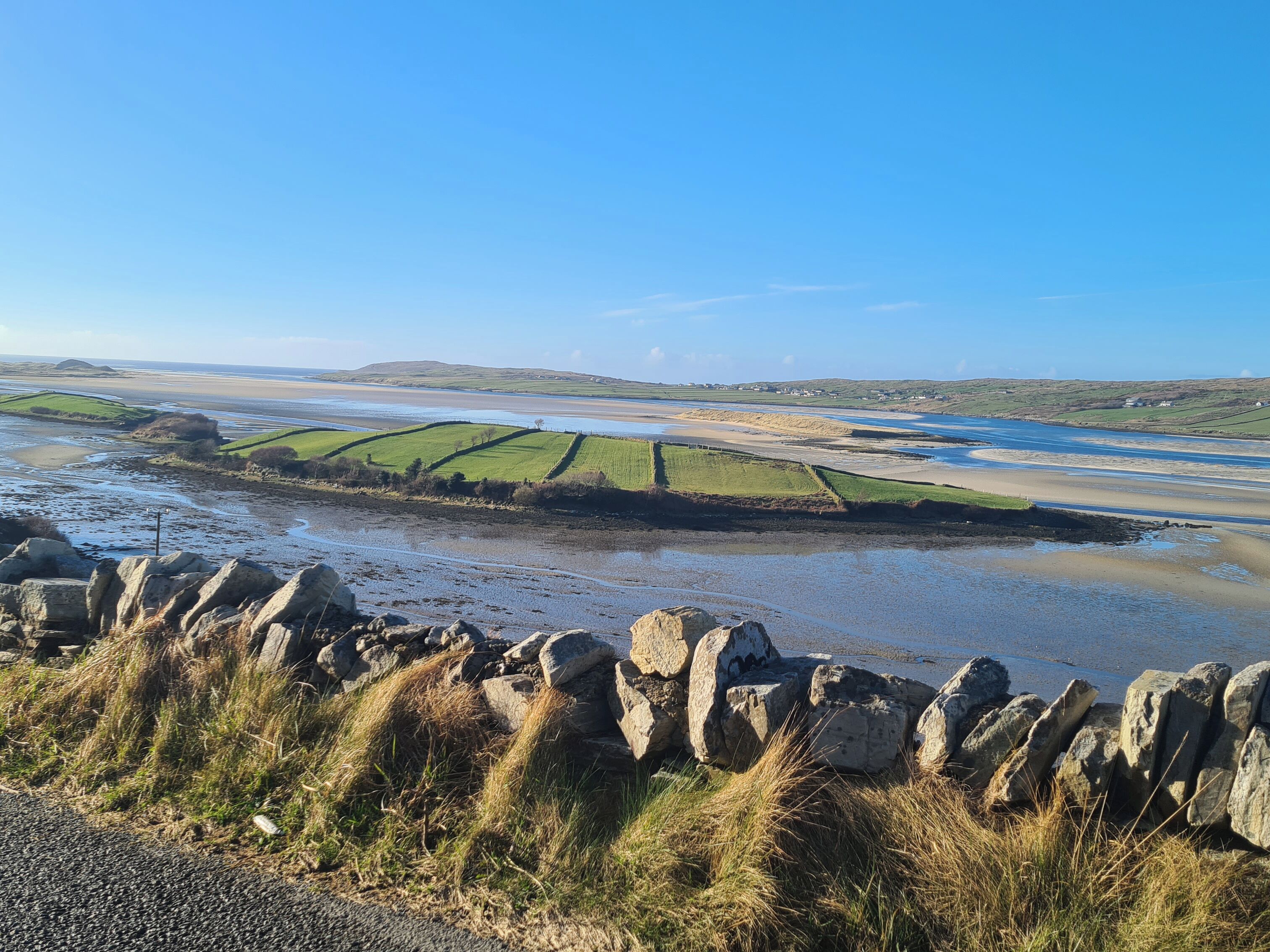 A coastal landscape with stone walls and grassy fields.