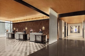A modern hotel lobby with reception desks, a patterned wall, and a geometric light fixture.