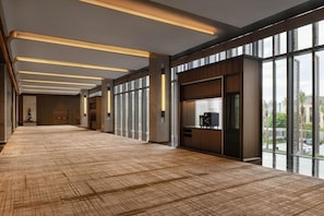 Un vestíbulo amplio con alfombra estampada, ventanas grandes e iluminación moderna.