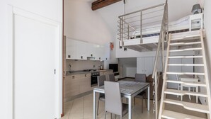 Une cuisine compacte avec une table et des chaises, une chambre en mezzanine avec un lit superposé et un escalier.