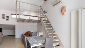 Un espace de vie compact comprenant une chambre en mezzanine, un coin repas et une cuisine.