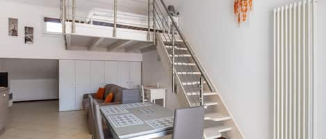 A compact living space with a loft bedroom, a dining area, and a kitchen.