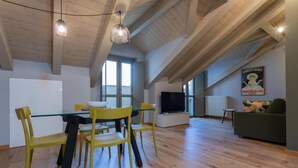 Een ruime woonkamer met een eettafel en stoelen, een televisie en een bank.