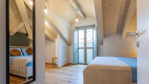 Een slaapkamer met een groot bed, een spiegel en een deur naar een balkon.