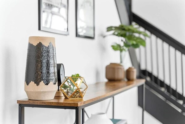A modern interior with a wooden table displaying a ceramic vase and a decorative geometric container.
