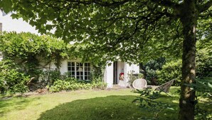 Een tuin met een wit huis, een schommel en een gazon.