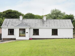 A single-story white house with a grey roof, a small porch, and a well-maintained lawn. - Daffodil Cottage (Grange)