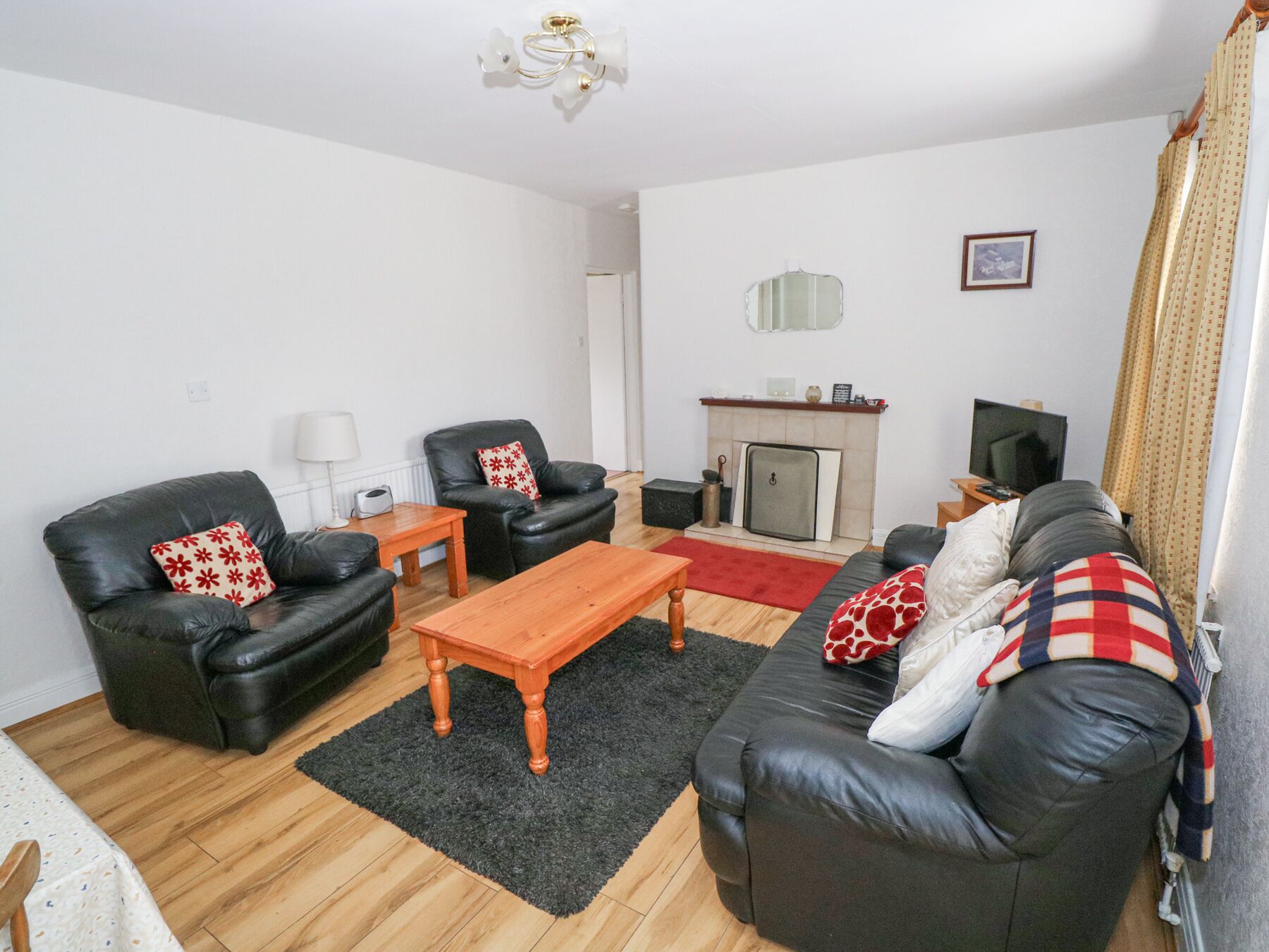 A living room with a fireplace, leather sofas, a wooden coffee table, and a television.