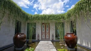 A serene courtyard with a central pathway, large vases, and lush greenery. - Luxury Spacious Family 5BR Villa Big Pool & Garden (Canggu)
