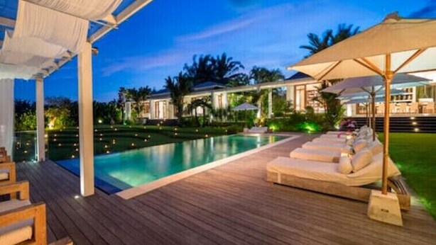 A poolside area with lounge chairs and umbrellas, surrounded by a wooden deck and a pool. - Luxury Spacious Family 5BR Villa Big Pool & Garden (Canggu)