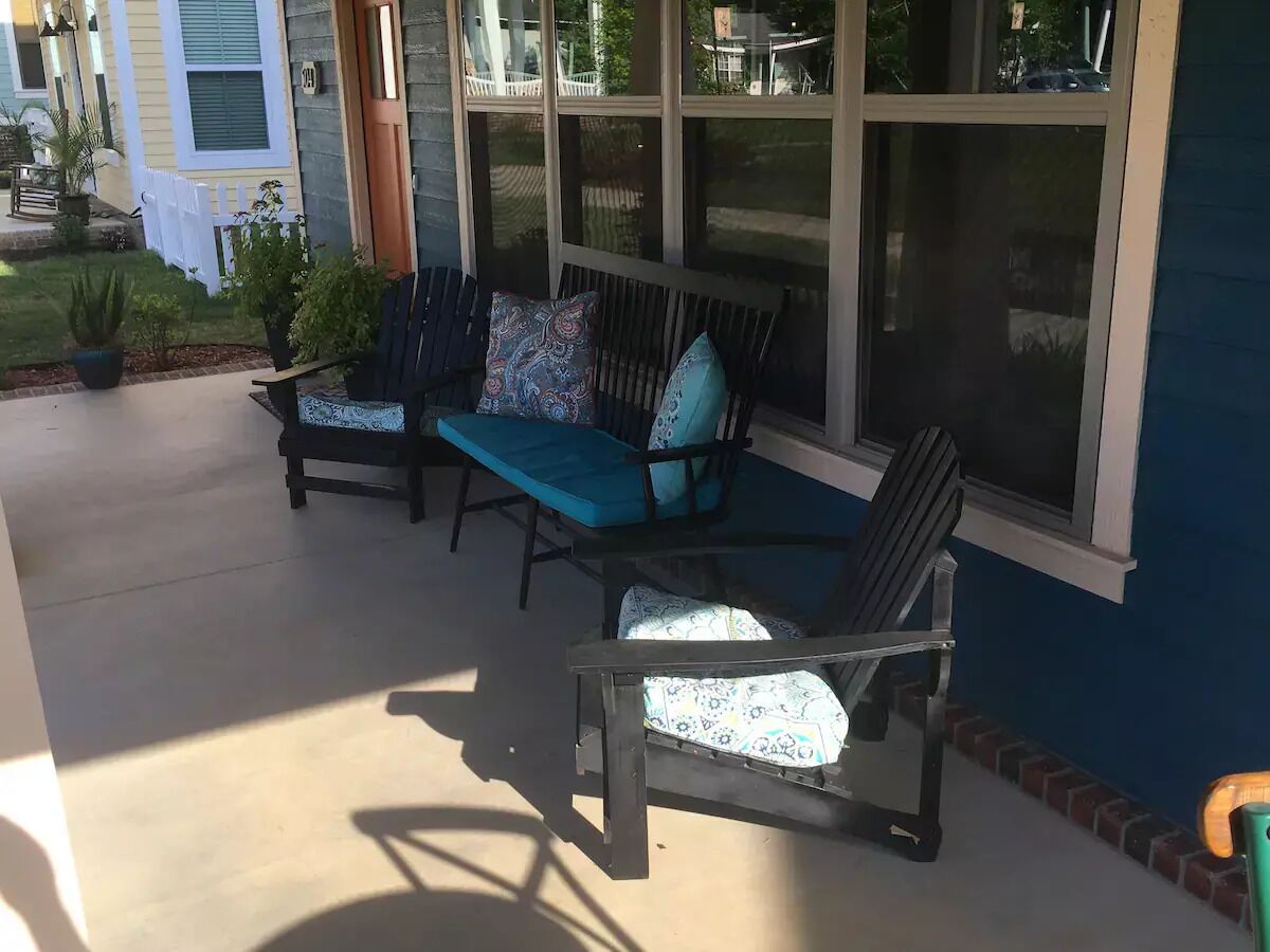 An outdoor patio with two Adirondack chairs, one with a patterned cushion and the other with a solid color cushion.