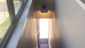 Portaat, joiden yläpäässä on valaisin, ja portaat johtavat avoinna olevaan oveen.