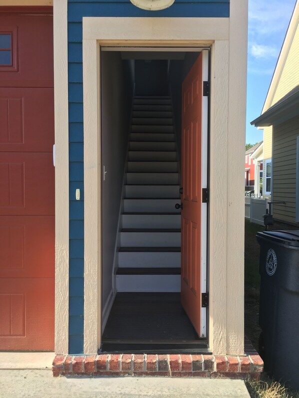 A residential building with a red garage door, a blue exterior, and a brick foundation. - Legacy Park Apartment next to Harding University (Searcy)