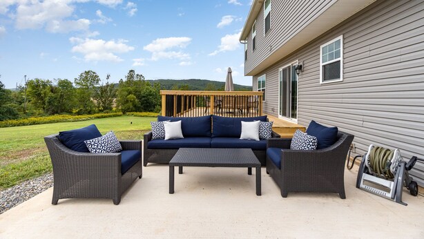 An outdoor patio with a dark wicker sofa set, a matching coffee table, and a wooden deck area.