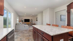 A spacious kitchen with granite countertops, wooden cabinets, and a central island.