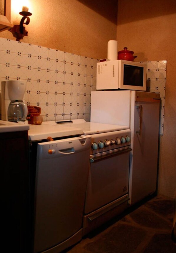Uma cozinha compacta com fogão, forno, micro-ondas e geladeira.