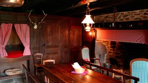 Un coin repas rustique, avec des meubles en bois, un mur en pierre et un luminaire suspendu.