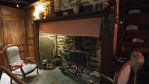 Une pièce rustique avec une cheminée en pierre, des meubles en bois et un mur en pierre.