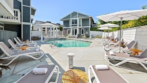 Un espace aménagé au bord de la piscine, avec des chaises longues, une piscine et un bâtiment au design moderne.