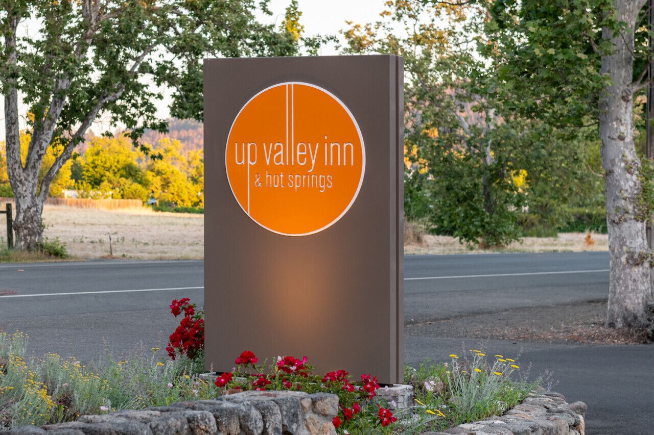 A sign for Up Valley Inn & Hot Springs with a circular logo and text.