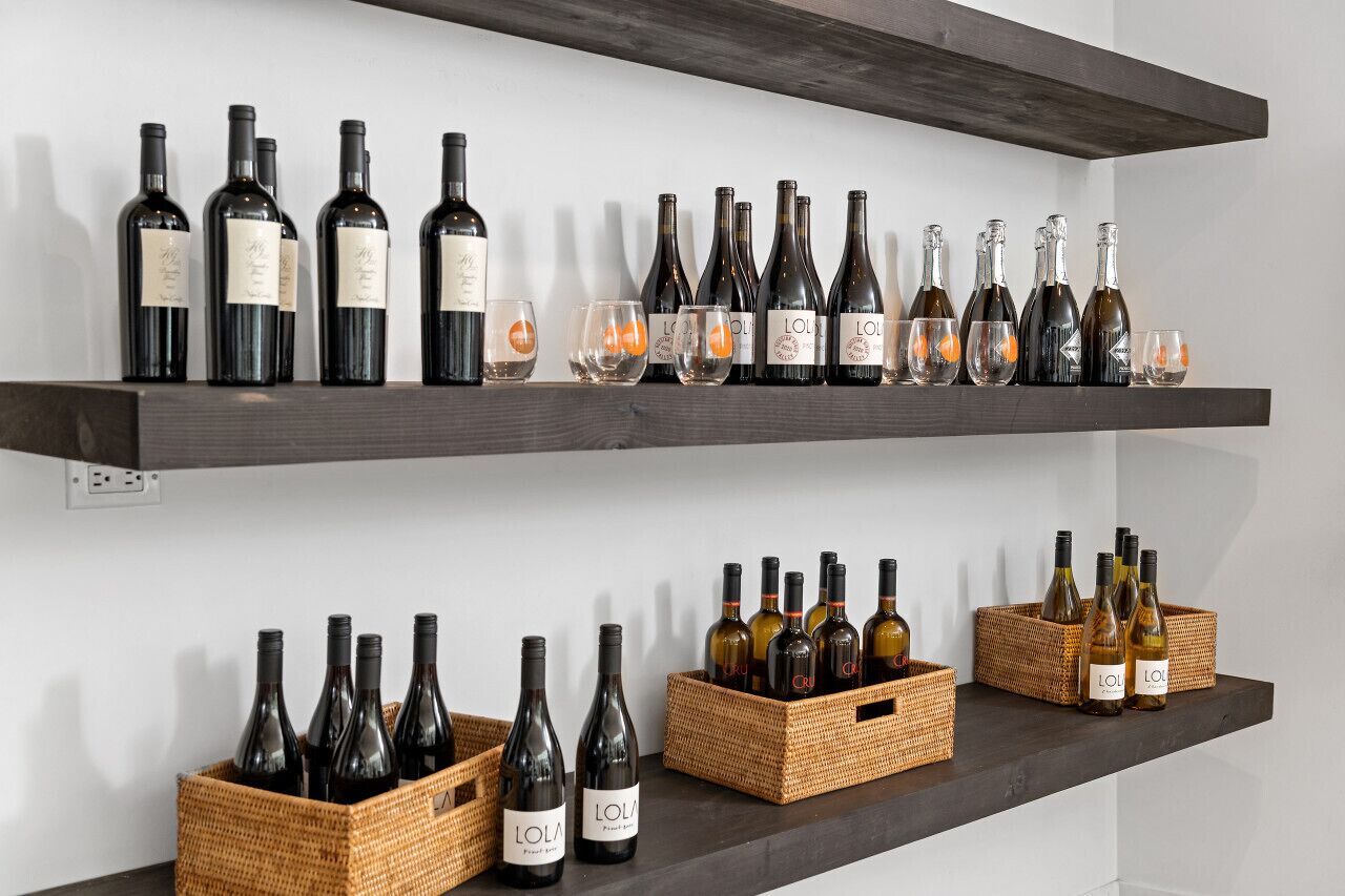 Two shelves with wine bottles and glasses.