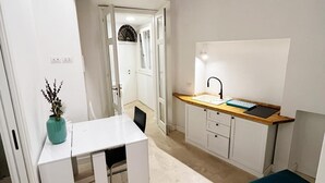 A compact kitchen with a white countertop, a sink, and a wooden ceiling. - Repetita Juvant (Rome)