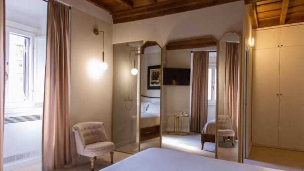 A bedroom with a large bed, a chair, a wardrobe, and a mirror. - Repetita Juvant (Rome)