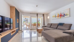 A modern living room with a flat-screen TV, a sofa, a coffee table, and a painting of sailboats. - Villa Dvor (Vodnjan)