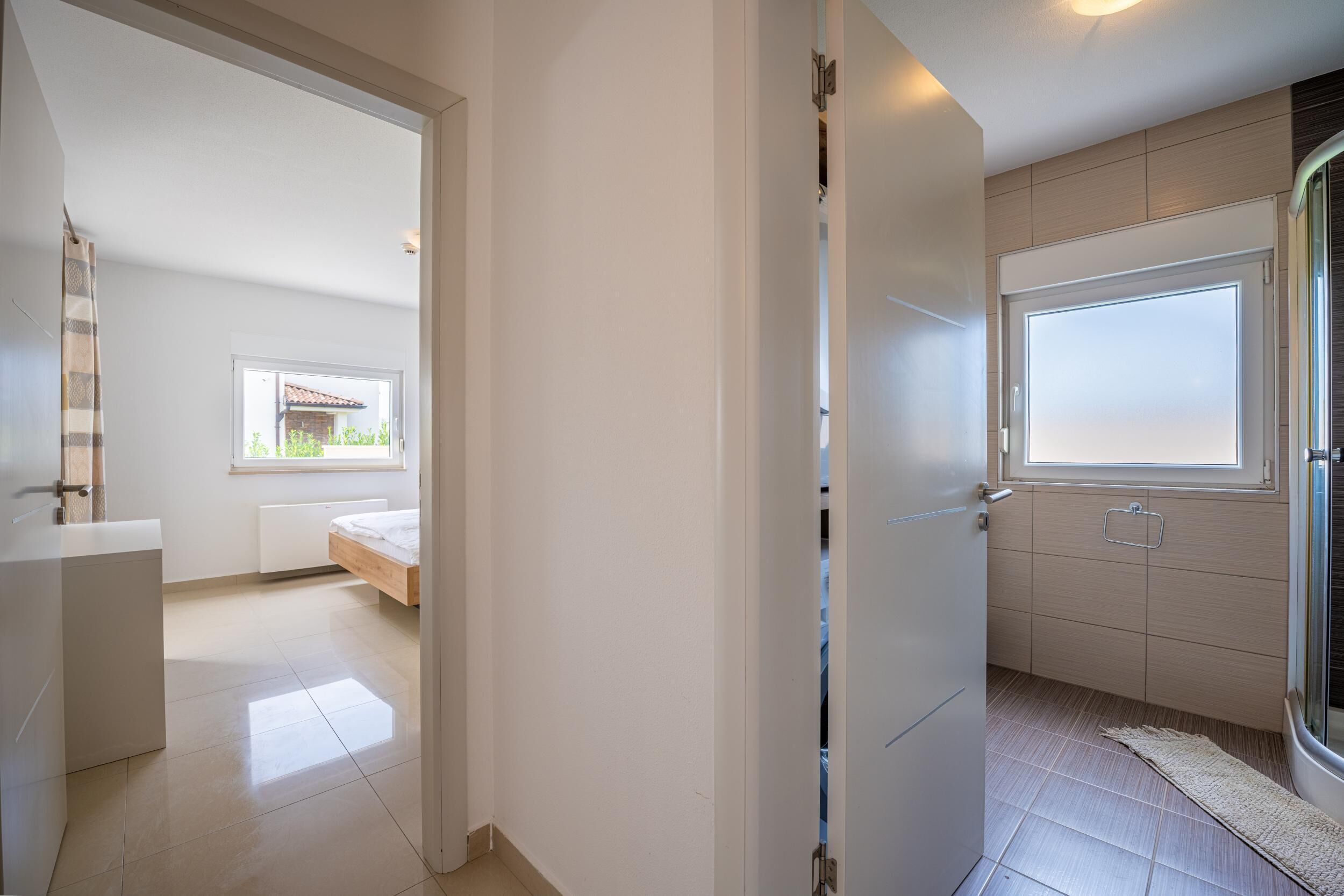 Ein modernes Badezimmer mit einem großen Fenster, einer Duschkabine und einer Toilette.