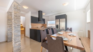 A modern kitchen with a central island, dark cabinetry, and a stone accent wall. - Villa Dvor (Vodnjan)