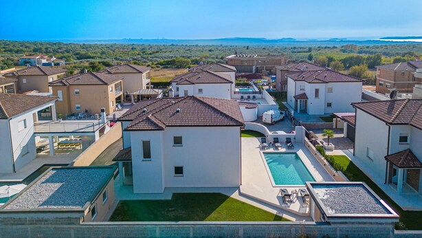 A residential area with modern houses, a swimming pool, and a view of the sea. - Villa Dvor (Vodnjan)